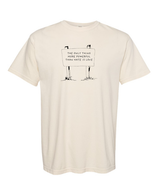 Beige t-shirt with a graphic design that says The Only Thing more Powerful than hate is love on a white background